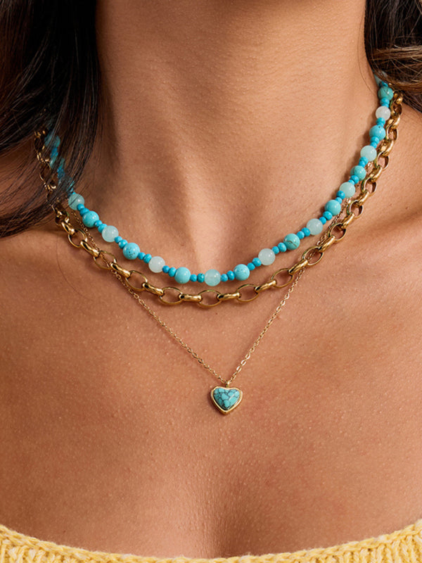 Necklace with turquoise beads and gold chain on a person wearing a yellow top.