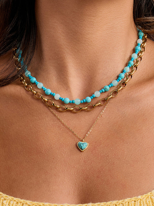 Necklace with turquoise beads and gold chain on a person wearing a yellow top.