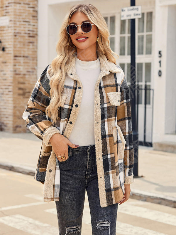 Woman wearing a plaid coat with a white shirt and jeans, standing on a street.